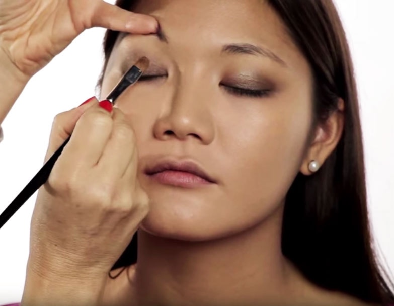 A young woman with olive skin being made up with golden colors by Louise Wittlich, makeup artist